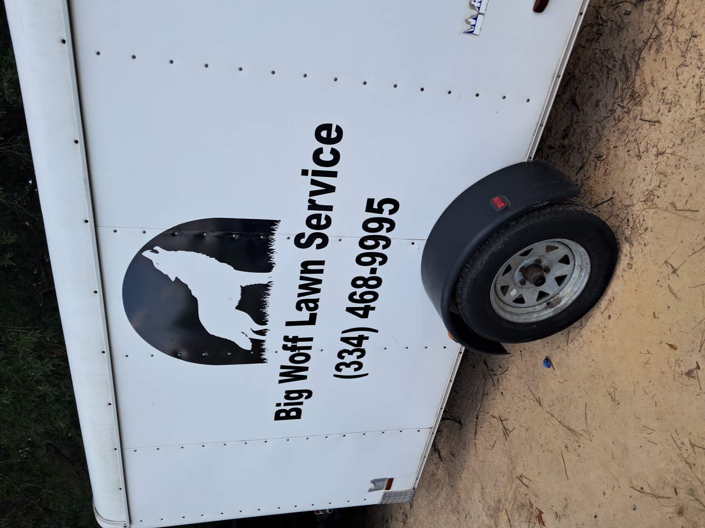 Big Woff Lawn Service howling wolf logo and custom lettering installed on a white utility trailer