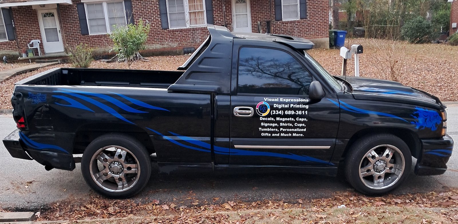 Passenger side of the Visual Expressions Nasty truck with custom blue vehicle graphics and door lettering