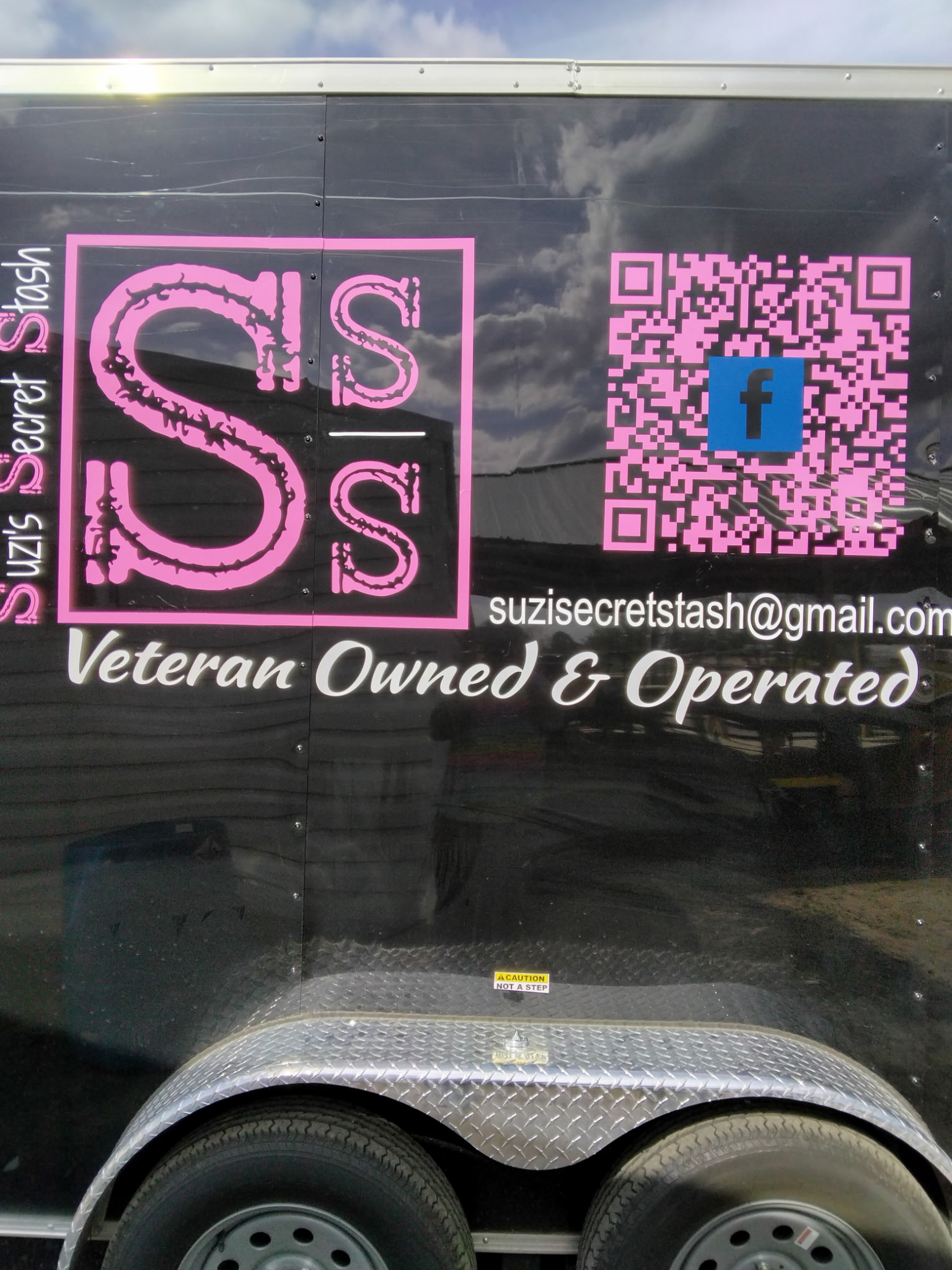 Custom pink and white business lettering installed on a black trailer
